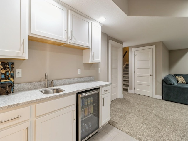 kitchen with light carpet, light stone counters, beverage cooler, and sink