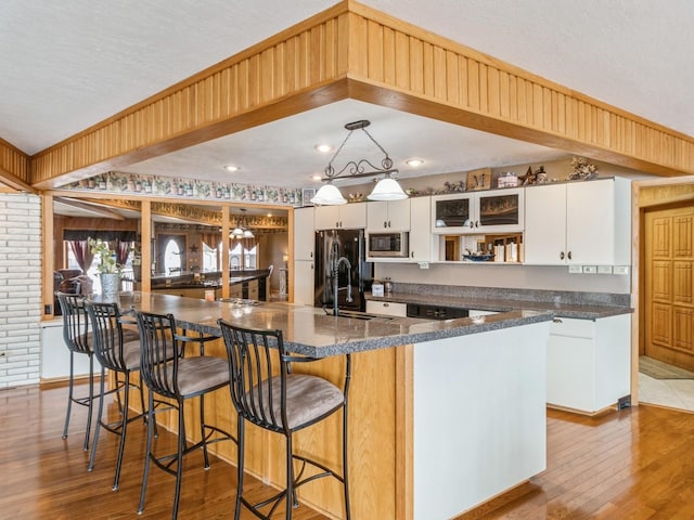 kitchen with sink, decorative light fixtures, a center island with sink, white cabinetry, and stainless steel microwave