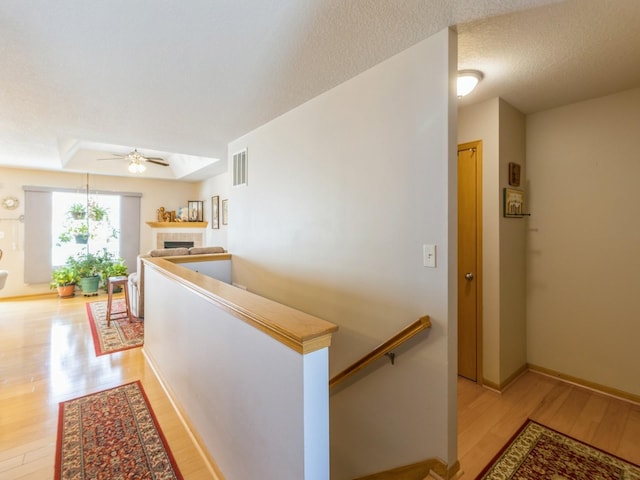 hallway with light hardwood / wood-style floors and a textured ceiling