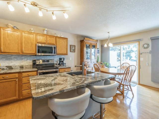 kitchen featuring hanging light fixtures, a kitchen breakfast bar, stainless steel appliances, and a kitchen island with sink