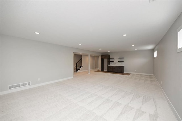 basement with bar and light carpet