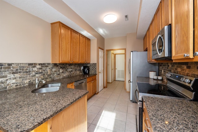 kitchen featuring sink, appliances with stainless steel finishes, kitchen peninsula, decorative backsplash, and dark stone counters