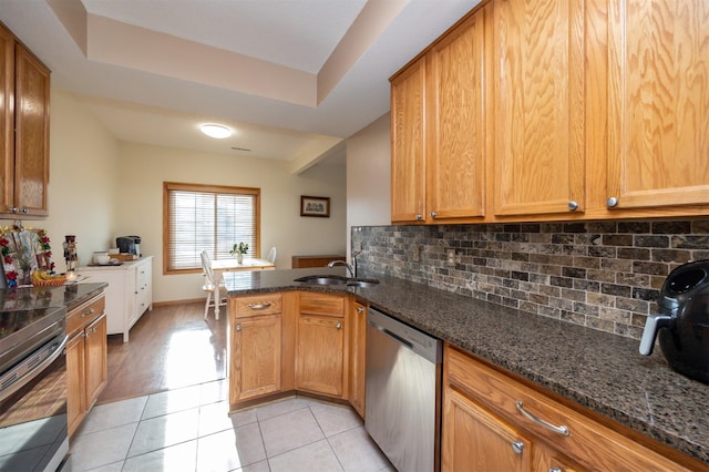 kitchen with stove, stainless steel dishwasher, light tile patterned floors, and dark stone counters