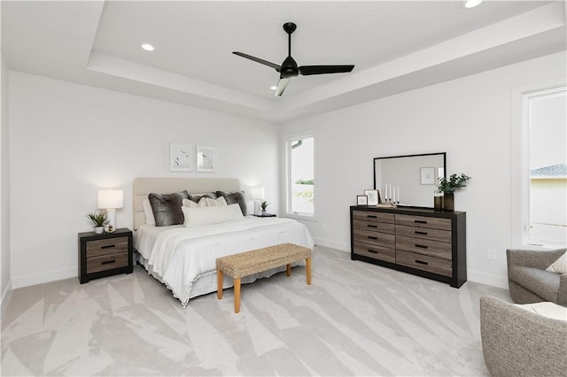 carpeted bedroom with a raised ceiling and ceiling fan