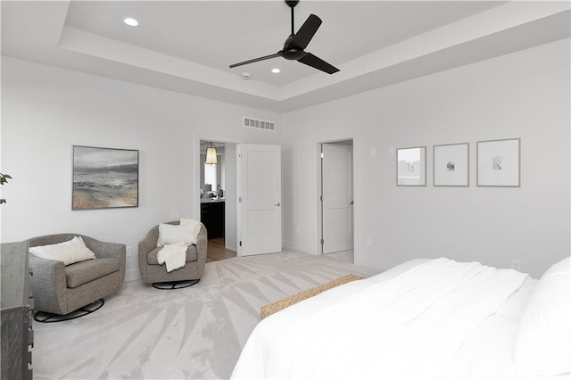 bedroom featuring a raised ceiling, light carpet, and ceiling fan