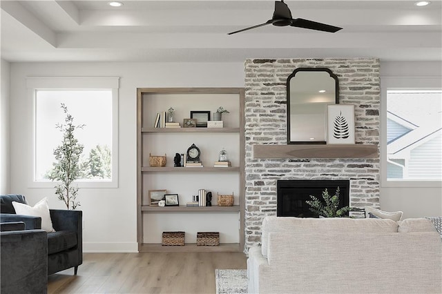 interior space featuring a stone fireplace, light hardwood / wood-style flooring, built in features, and ceiling fan