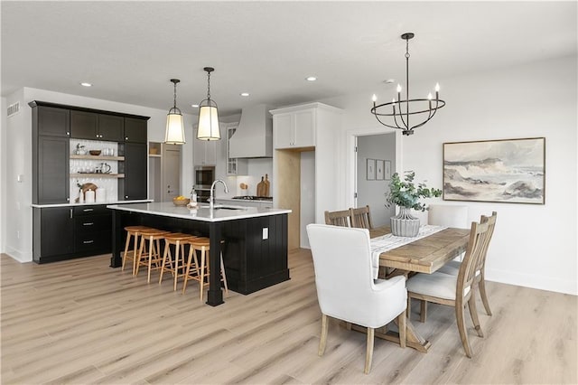 dining space featuring sink, an inviting chandelier, and light hardwood / wood-style floors