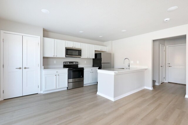 kitchen with light hardwood / wood-style floors, sink, white cabinetry, and stainless steel appliances