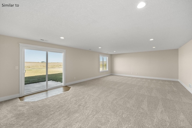 unfurnished room featuring a textured ceiling and light carpet