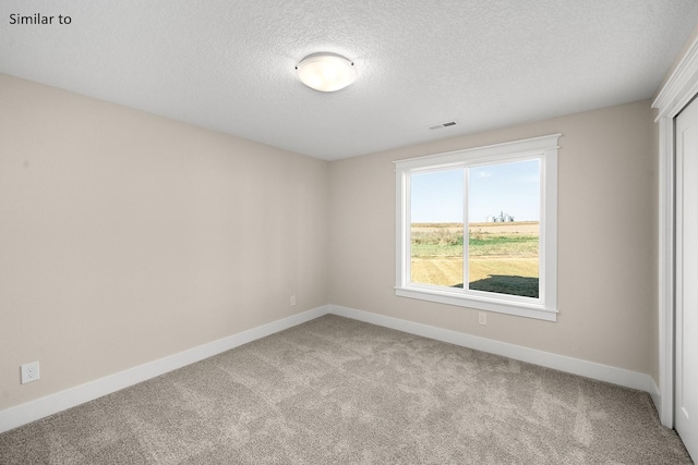 spare room with a textured ceiling and light carpet