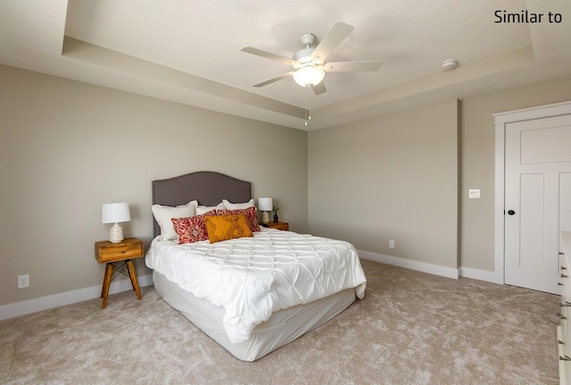 bedroom featuring ceiling fan, light carpet, and a tray ceiling