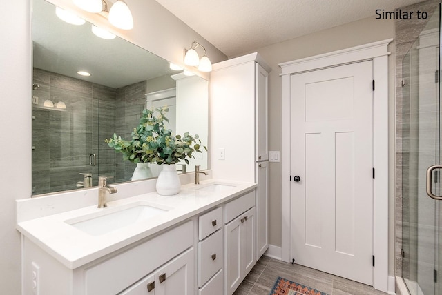 bathroom with vanity, a shower with shower door, and a textured ceiling