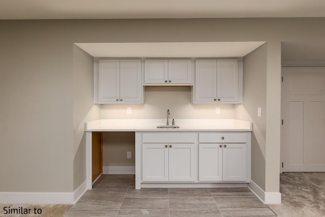 kitchen featuring light colored carpet, white cabinetry, and sink