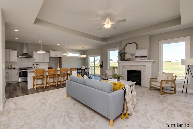 living room featuring a tray ceiling, ceiling fan, and sink