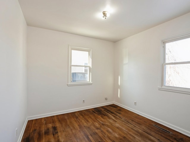 spare room with a healthy amount of sunlight and dark hardwood / wood-style flooring