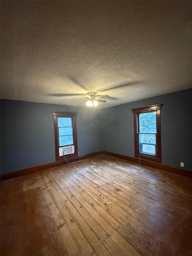 spare room featuring a textured ceiling, hardwood / wood-style flooring, and a healthy amount of sunlight