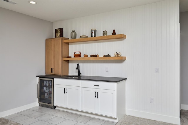 bar featuring beverage cooler, wooden walls, sink, white cabinets, and light tile patterned flooring