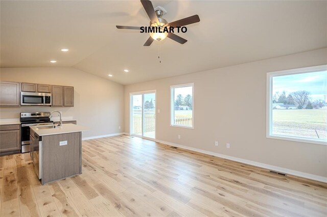 kitchen with ceiling fan, stainless steel appliances, light hardwood / wood-style floors, and a center island with sink