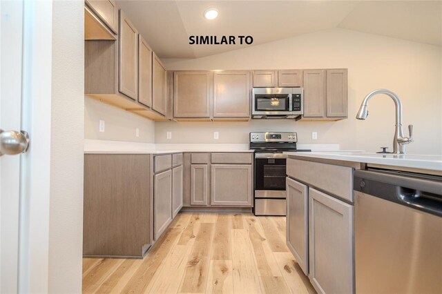 kitchen with vaulted ceiling, appliances with stainless steel finishes, and light hardwood / wood-style floors