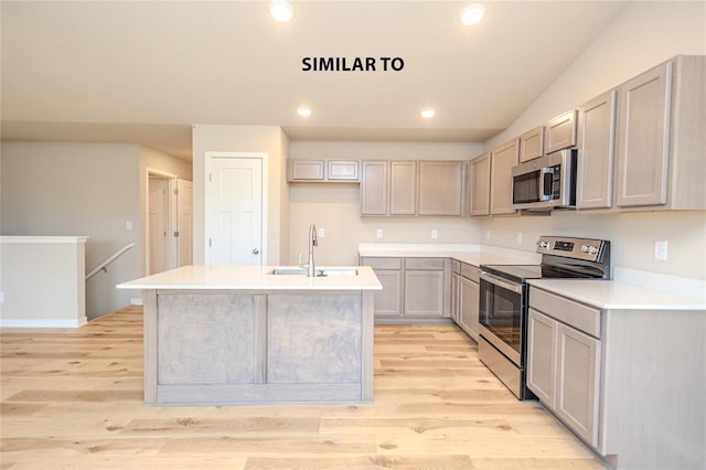 kitchen featuring gray cabinets, appliances with stainless steel finishes, sink, a center island with sink, and light hardwood / wood-style flooring