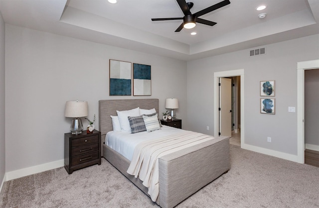 carpeted bedroom featuring a raised ceiling and ceiling fan