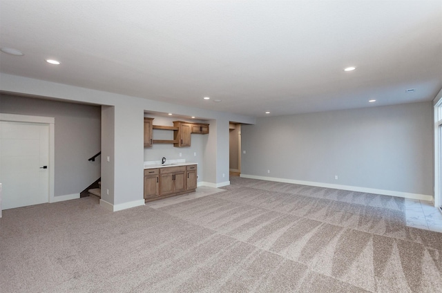 unfurnished living room with sink and light colored carpet