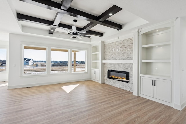 unfurnished living room featuring a stone fireplace, coffered ceiling, built in features, baseboards, and light wood-type flooring