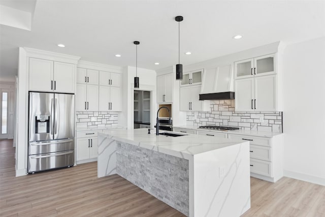 kitchen with appliances with stainless steel finishes, a center island with sink, and white cabinets