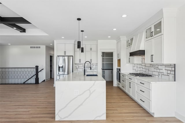 kitchen with stainless steel appliances, a sink, a center island with sink, and decorative light fixtures