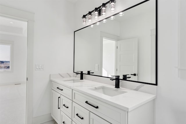 full bathroom with double vanity, baseboards, and a sink