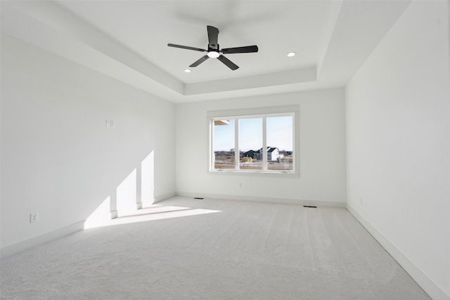 unfurnished room with light carpet, recessed lighting, a raised ceiling, and baseboards