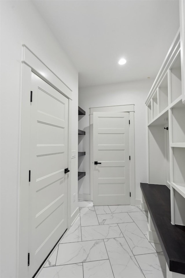 mudroom with recessed lighting, marble finish floor, and baseboards