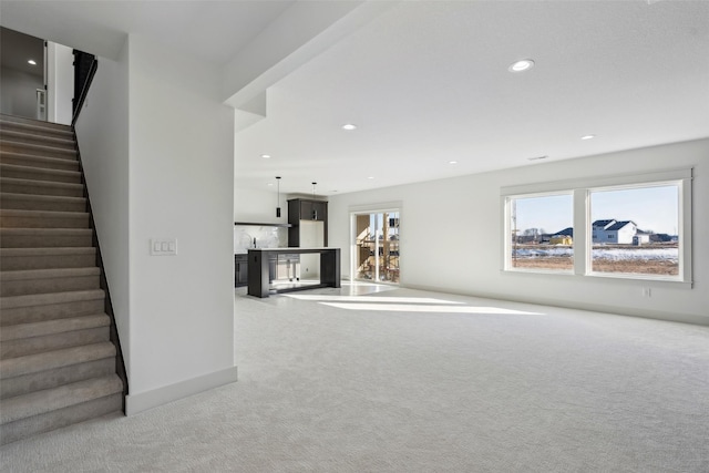 unfurnished living room with light carpet and stairway