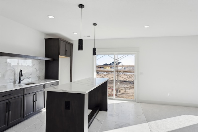 kitchen featuring a center island, marble finish floor, hanging light fixtures, decorative backsplash, and a sink