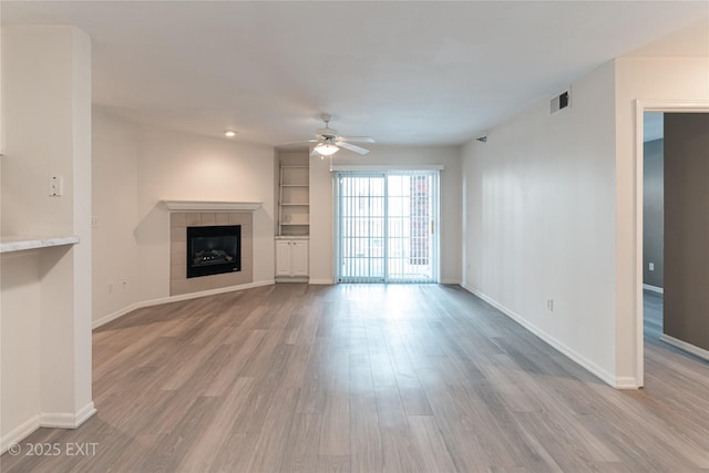 unfurnished living room with ceiling fan, light hardwood / wood-style flooring, and a tiled fireplace