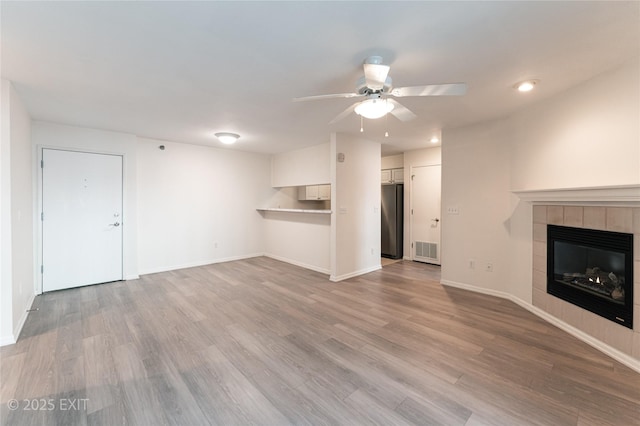 unfurnished living room featuring ceiling fan, a fireplace, and light hardwood / wood-style flooring