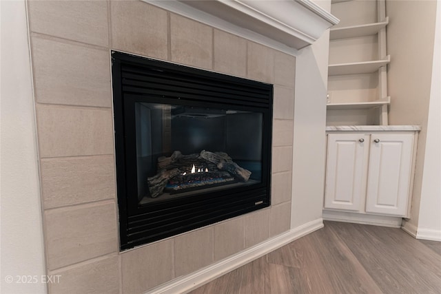 interior details featuring a tile fireplace and hardwood / wood-style flooring