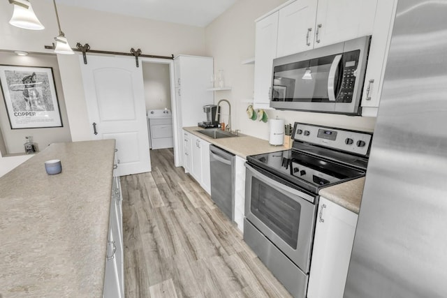 kitchen featuring white cabinetry, sink, a barn door, pendant lighting, and appliances with stainless steel finishes