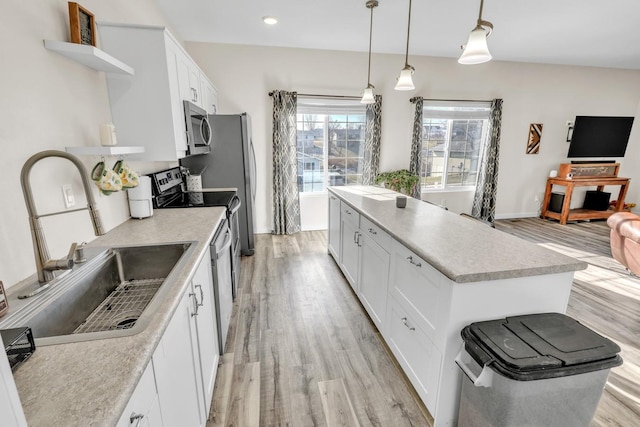 kitchen with white cabinets, stainless steel appliances, a kitchen island, and hanging light fixtures