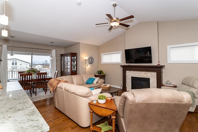 living room with a stone fireplace, ceiling fan, lofted ceiling, and hardwood / wood-style flooring