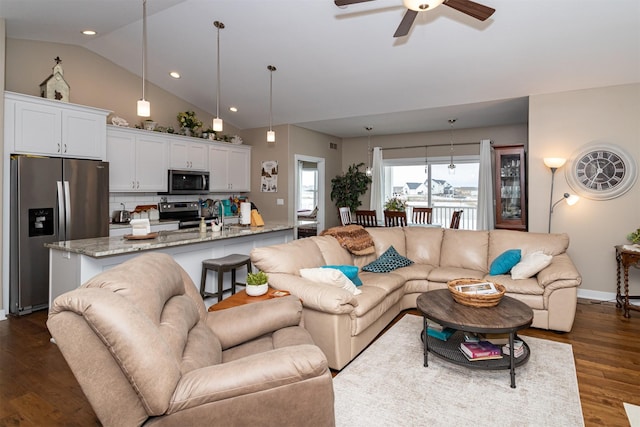 living room with ceiling fan, dark wood-type flooring, and vaulted ceiling