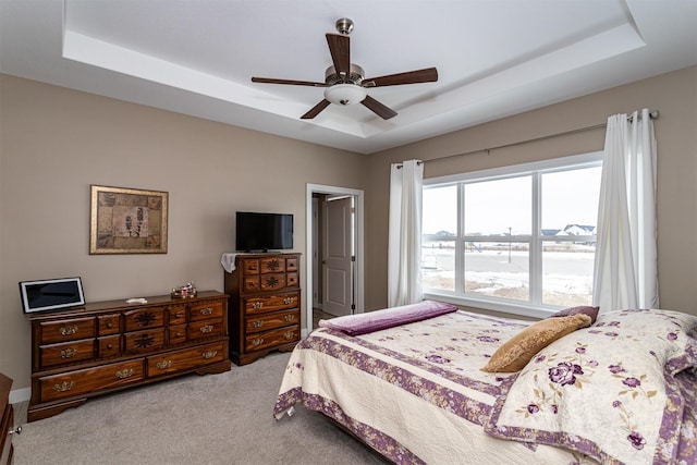 carpeted bedroom with a tray ceiling and ceiling fan