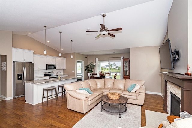 490 Bella Vista Ct, Huxley, IA 50124 - living room featuring vaulted ceiling, dark wood-style flooring, a ceiling fan, baseboards, and a stone fireplace