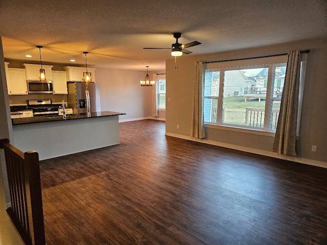 kitchen with pendant lighting, white cabinets, ceiling fan with notable chandelier, dark hardwood / wood-style floors, and stainless steel appliances