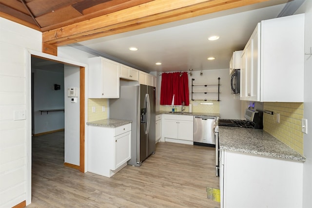 kitchen featuring backsplash, white cabinetry, light hardwood / wood-style flooring, and stainless steel appliances