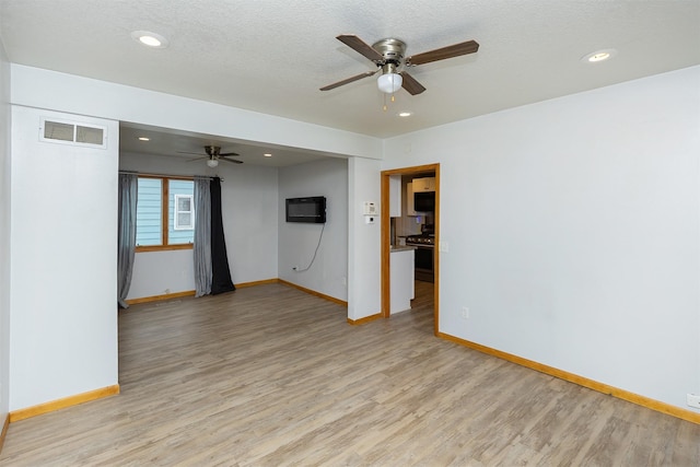 unfurnished room featuring ceiling fan, light hardwood / wood-style floors, and a wall mounted AC