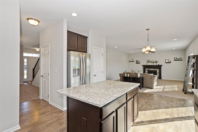 kitchen featuring a center island, light hardwood / wood-style flooring, hanging light fixtures, dark brown cabinets, and stainless steel fridge with ice dispenser