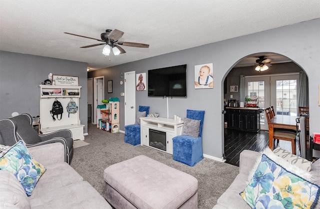 carpeted living room featuring ceiling fan and a textured ceiling