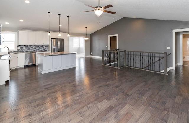 kitchen with white cabinetry, stainless steel appliances, backsplash, decorative light fixtures, and a kitchen island