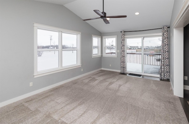 unfurnished room featuring carpet, vaulted ceiling, ceiling fan, and plenty of natural light